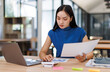 © David - Business asian woman working in the office with working notepad, tablet and laptop documents tax, report, accounting, statistics, and analytical research concept