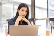 © David - Portrait of Business Asian woman sitting at at laptop and thinking of problem solution, working schedule for employee writing report into notebook while using laptop computer in coworking space