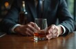 © miss irine - Close-up of man hand in suit holding glass of whiskey. Bottle stands on wooden table. Concept of relax with aged alcohol drink after hard working day.