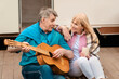 © Prostock-studio - Senior man playing guitar and singing song to his beloved wife near motorhome outdoors