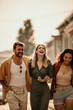 © La Famiglia - Diverse group of stylish friends laughing and strolling down a sunlit city street