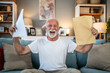 © Migma_Agency - Excited senior man receiving good news at home