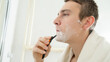 © Mariia - Handsome man shaving in the bathroom.