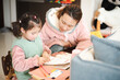 © fotozlatko - A Chinese woman is helping her daughter with her English and math homework at the small table in their living room