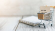 © Bonsales - Miniature shopping cart carrying buy now pay later note beside lined notepad, representing flexible digital purchasing strategy