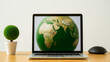 © Bonsales - Laptop displaying a green Earth promoting environmental awareness during an Earth Day event, symbolizing global responsibility and sustainability