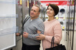 © JackF - Mature man and woman standing in salesroom of appliance shop and choosing refrigerator.