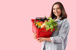 © Pixel-Shot - Young woman with shopping basket of fresh vegetables on pink background