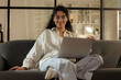 © Pixel-Shot - Female African-American programmer working with laptop on sofa in office at night