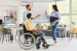 © Pixel-Shot - Team of designers with man in wheelchair working near flipchart in office