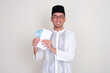 © KrishnaTedjo - Muslim man smiling happy while showing money inside an envelope