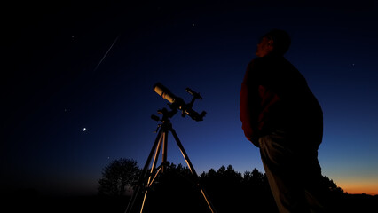 Wall Mural - amateur astronomer looking at the evening skies, observing planets, stars, moon and other celestial 