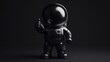 © BerkahStock - Black astronaut figurine giving thumbs up against dark background.