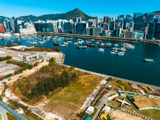Poster - Aerial panorama of Hong Kong, China showcases a cityscape by the water. Mountains rise behind modern buildings, with boats dotting the harbor in a wide view.