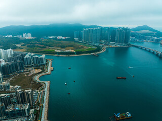 Aufkleber - Aerial panorama of Hong Kong, China, featuring buildings lining the coast next to deep blue water and distant mountains under a cloudy sky.