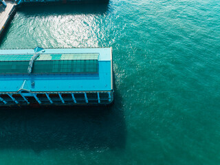 Poster - Aerial panorama of Hong Kong city pier extending into turquoise waters. Buildings line the coast in this wide, top-down perspective of the urban landscape.