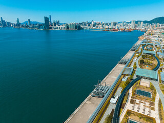 Aufkleber - Aerial panorama captures Hong Kong, China, showcasing a wide cityscape and harbor under a blue sky.  Buildings line the coast and green spaces are visible.