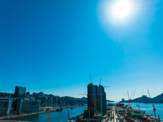 Aufkleber - Aerial panorama of Hong Kong city under a bright sun. View captures urban buildings, waterfront, and harbor in a wide cityscape.