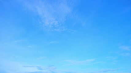 Wall Mural - A dynamic timelapse, the sky changes with an energetic flow, as soft clouds scatter across the vibrant blue expanse, depicting the unyielding motion of time and nature's endless transformation.
