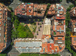 © AmazingAerialAgency - Aerial view of beautiful rooftops and greenery in a sunny residential neighborhood with a park and square, Gracia, Barcelona, Spain.