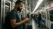 © Raphael - a man, standing inside a modern subway train. Focusing intently on his smartphone with the other