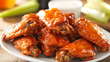 © Aekkawass - Buffalo wings coated in spicy, tangy sauce are served on white plate with side of ranch dressing and fresh celery sticks. crispy, saucy texture makes them popular appetizer or game day snack