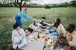 © qunica.com - A group of friends gathers for a picnic, sharing food and drinks, in a lush green park setting. They enjoy each others company and the natural scenery, creating a joyful and relaxed atmosphere.