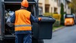 © LaCosta - A garbage collector emptying a plastic waste bin into a truck in a residential area, showcasing community cleanliness and waste management efforts