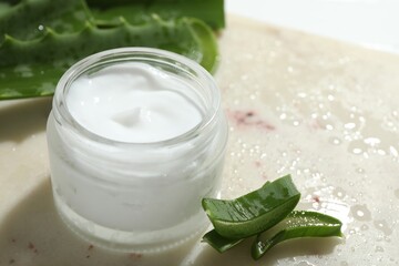 Wall Mural - cream and aloe leaves on light background, closeup. space for text