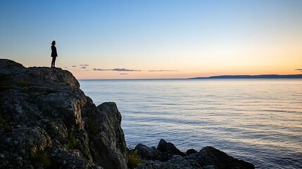 Aufkleber - Woman standing on rocky shore during sunset overlooking calm water with colorful sky and distant hills : Generative AI