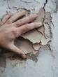 © Generative AI - Close up of a hand pressing against peeling plaster showing texture and detail of the wall material : Generative AI