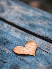 Poster - Heart shaped dry leaf lying on rustic wooden surface symbolizing love and nature in a beautiful natural setting : Generative AI