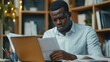 © OLEKSANDR - Serious black businessman using laptop and doing paperwork