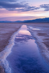 Wall Mural - A serene salt flat landscape at sunset, reflecting pastel skies and clouds in tranquil waters, framed by distant mountains under a purple-pink hue.