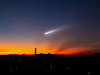 Wall Mural - comet over the city at sunset. comet tail in the sky, astronomical landscape. astrophotography of a 
