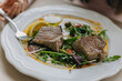 © Inna - A perfectly seared tuna steak on a white plate, with green salad and a glossy drizzle of sauce.