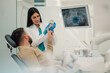 © Zamrznuti tonovi - Female dentist showing teeth model to patient in modern clinic