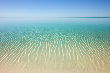 Wall Mural - Tranquil ocean scene with clear blue skies and gentle ripples on crystal-clear aqua water reflecting serene beauty.