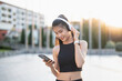 © Charlie's - Happy Active healthy asian woman listening music with headphones for mental health listening to audio for running inspiration.