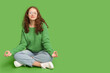 © Pixel-Shot - Portrait of relaxed young woman meditating on green background