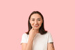 © Pixel-Shot - Young woman touching her nose on pink background