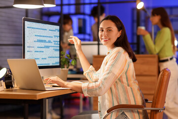 Female programmer working with computer in office at night