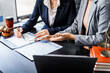 © Phushutter - Two female lawyers in business suits meet at wooden desk, shaking hands over contract paper. wooden gavel and scales justice as discuss legal compliance, corporate law, dispute resolution.