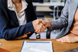 © Phushutter - Two female lawyers in business suits shake hands at wooden desk, finalizing legal agreement. wooden gavel and scales represent justice as they discuss corporate law, compliance, dispute resolution.