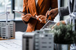 © Phushutter - Two businesswomen sit at a desk in a meeting, discussing property development while building a model of city tower. real estate investments, zoning laws, sustainable energy solutions. net zero