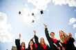 © deagreez - Joyful group of graduates celebrating their achievement by tossing caps in the air on a sunny day