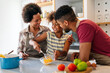 © NDABCREATIVITY - Happy black family in the kitchen having fun and cooking together. Healthy food at home.