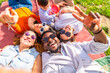 © unai - Happy friends taking a selfie while lying on a blanket in a park