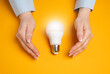 © Andrii Yalanskyi - Hands protect the light bulb idea. Concept of intellectual property protection. Innovation security. Creative defense, legal protection, and ownership of original concepts.