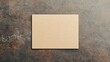© Tanakrit - A blank brown card rests on a textured surface, offering a simple yet versatile canvas for creativity or communication.